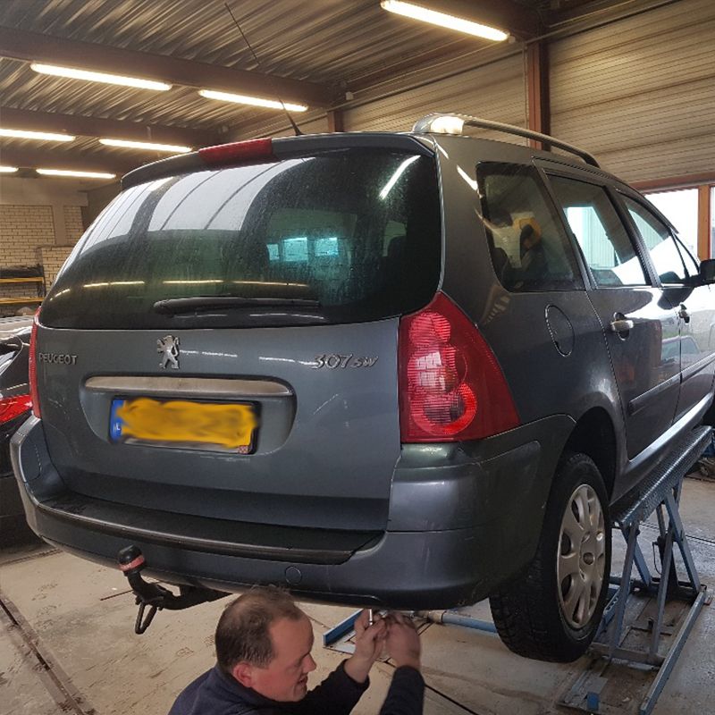 Monteur controleert de achterzijde van een Peugeot 307 SW na schadeherstel