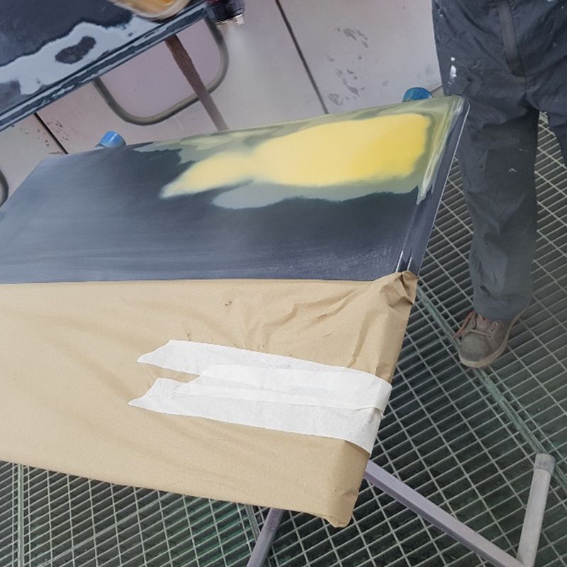 Spuiter werkt met verfspuit aan een gerepareerd paneel