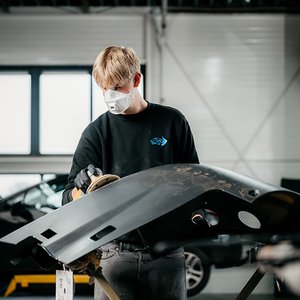 Monteur schuurt een bumper voor het spuitproces