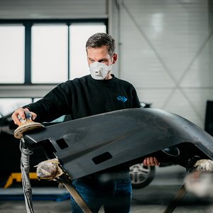 Monteur werkt met de schuurmachine aan een bumper