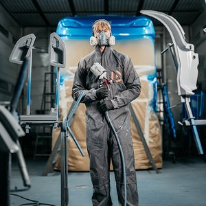 Spuiter in beschermende kleding klaar om een truckcabine te spuiten